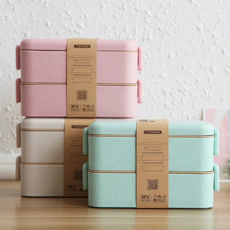 Stack of pink and green lunch boxes with brown packaging on a wooden surface.