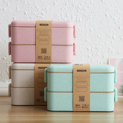 Stack of pink and green lunch boxes with brown packaging on a wooden surface.